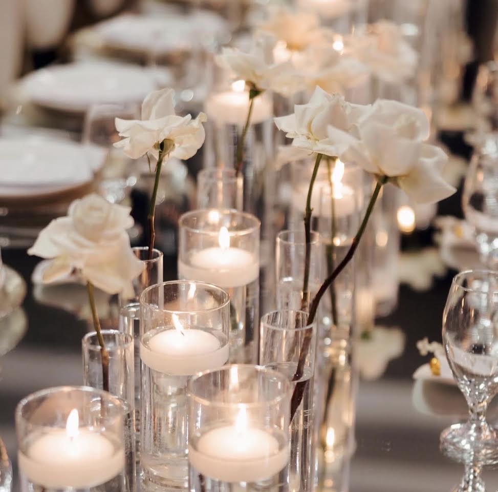 White roses and floating candles on a mirrored table