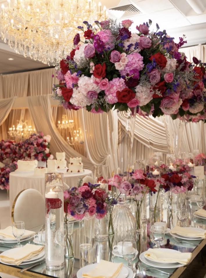 Tall jewel-toned floral centerpiece over a mirrored table